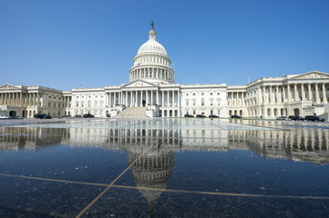 Scenic view of the US Capitol Building in Washington, DC reflecting on water under bright blue sky