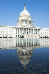 Bright scenic view of the US Capitol Building in Washington, DC reflecting on water under clear blue sky
