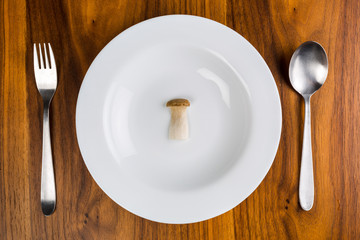 Single mushroom on a white saucer on a wooden table