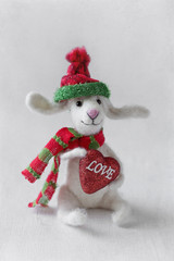 Woolen handmade toy bunny with a heart on the background with a texture .Felted wool toy.