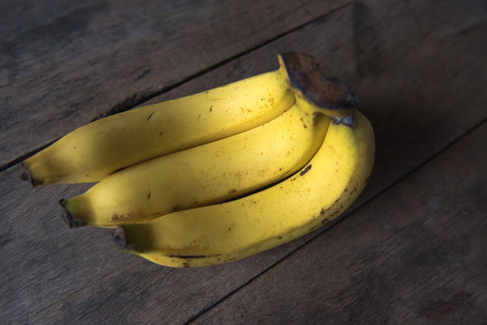 ripe yellow Fresh bananas on wood background, light and Shadow