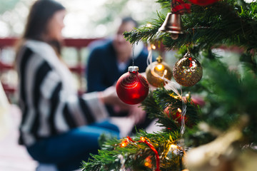 Christmas tree with ornamenst, with young couple in backgroung.