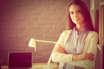 Young woman standing near desk with laptop