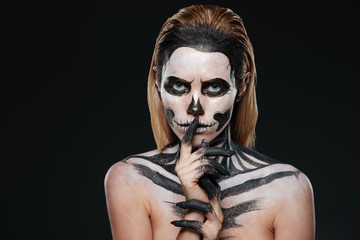 Woman with scared halloween makeup showing silence gesture