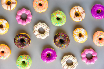 Treat and design. Collection of colorful donuts on the grey background. Top view.