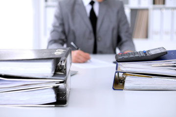Binders with papers are waiting to be processed with business woman back in blur. Accounting...