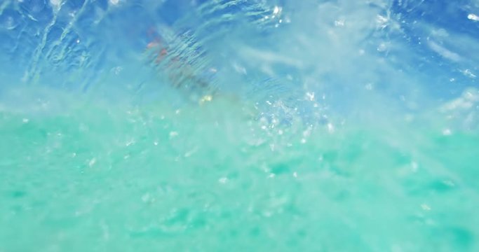 Young man kitesurfing in tropical blue ocean, splashing the camera in slow motion