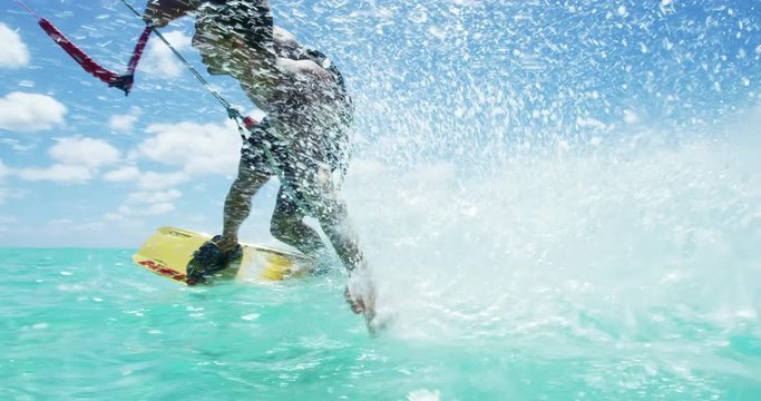 Young man kitesurfing in tropical blue ocean, extreme sport slow motion