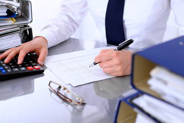 Fototapeta premium Bookkeeper or female financial inspector making report, calculating or checking balance. Internal Revenue Service checking financial document. Audit concept.