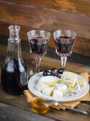 Cheese plate with grape and wine on wood