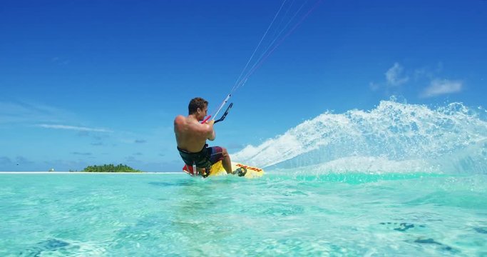 Young man kitesurfing in tropical blue ocean, extreme sport slow motion