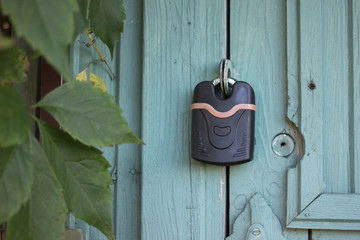 Closed padlock hanging on a wooden door