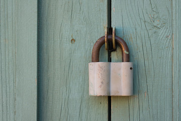 Closed padlock hanging on a wooden door