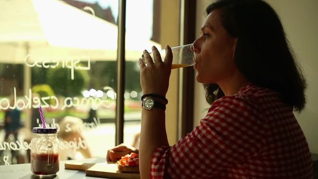 Young woman drinking orange juice in a cafe 
