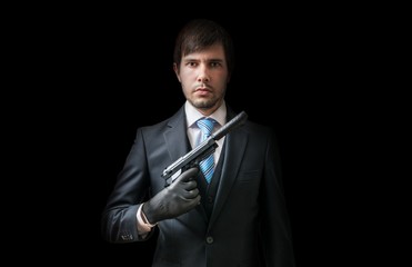 Hitman or murderer with pistol with silencer on black background. Low key photo.