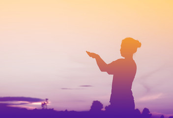 Silhouette of woman which Pray to god at sunset light.