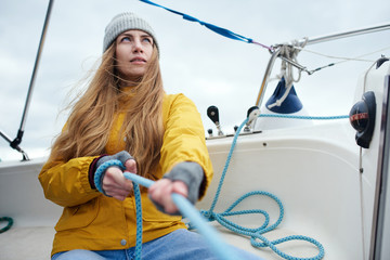 Young strong woman sailing the boat - obrazy, fototapety, plakaty