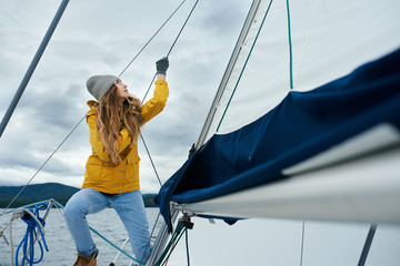 Young strong woman sailing the boat