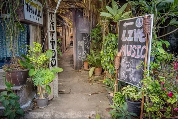 Foto op Plexiglas A long bright entrance to a dark hippie style tattoo bar © Stig Alenas