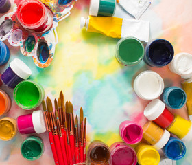 Paints, brushes and palette on the colorful background. The workplace of the artist. Banner for school