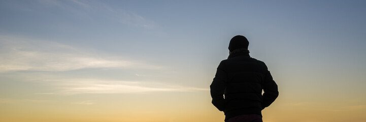 Wide backlit view on person with hands in pockets