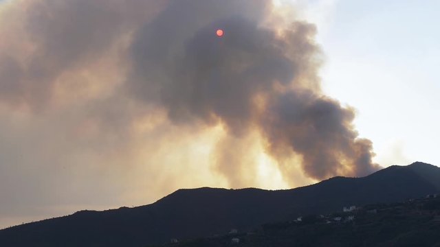 Canader in azione durante incendio su sole oscurato dal fumo