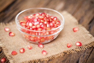 Pomegranate in bowl on sackcloth and wooden background