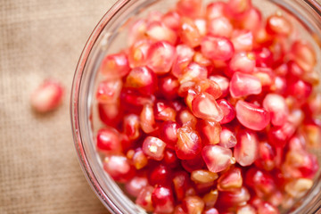 Pomegranate in bowl on sackcloth and wooden background