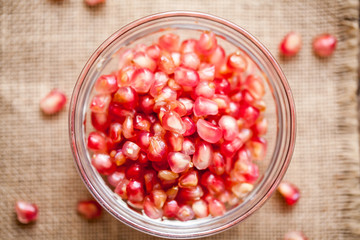 Pomegranate in bowl on sackcloth and wooden background