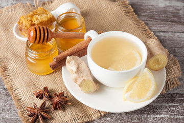 A white cup of green natural tea with ginger, lemon and honey on wooden rustic background. Healthy drink. Hot winter beverage concept.