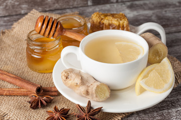 A white cup of green natural tea with ginger, lemon and honey on wooden rustic background. Healthy drink. Hot winter beverage concept.