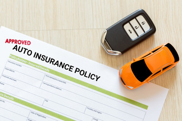 Top view of Approved auto insurance policy form with car key