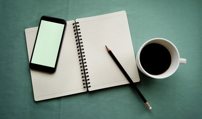 Tea in white cup with Journal book and smartphone