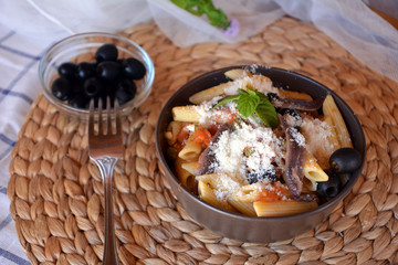 Delicious italian food penne ala puttanesca on a bowl on a table.