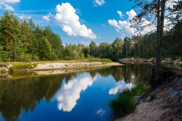 Fototapeta na wymiar Autumn landscape. The river flows through the forest, blue sky w
