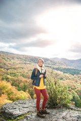 Naklejka na ściany i meble Beautiful woman with backpack against colorful sunny autumn fore