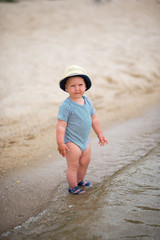 Adorable little kid boy standing on lonely beach