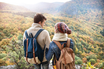 Obraz premium Beautiful couple with backpacks against colorful autumn forest