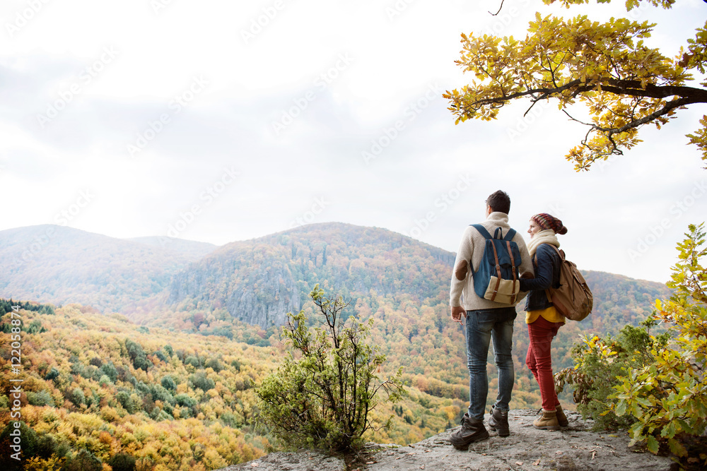 Wall mural Beautiful couple with backpacks against colorful autumn forest