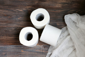 Paper towels, toilet paper rolls and piece of gauze on wooden table. Concept of purity, body care and cleanliness. Top view. Copy space.