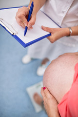 Nurse weighing pregnant woman in office
