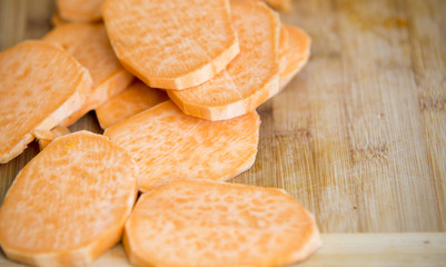 Raw pieces of sweet potatoes on wooden background