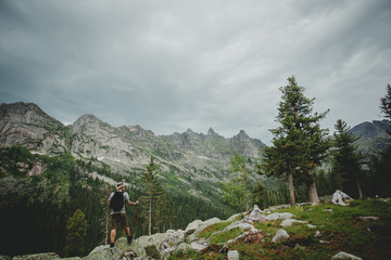 Hiker young man with backpack and trekking of cliff and looking