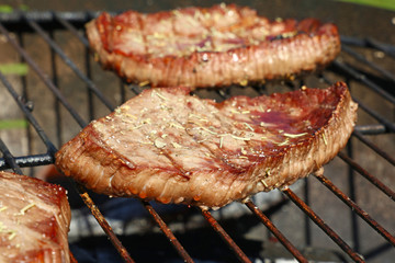 Grilled beef steaks cooking on barbecue grill