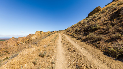 The road among the dry grass. The beautiful landscape of cliffs. Smith Rock state park, Oregon