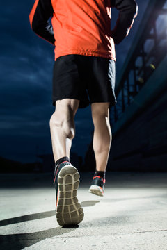 Young man running in the street at night.