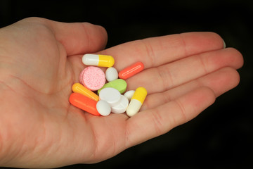 variety of pills and capsules lie in the palm of your hand