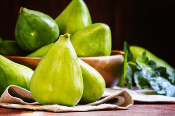 Sweet green figs in bowl, wooden background, selective focus