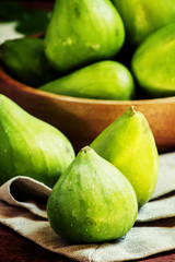 Sweet green figs in bowl, wooden background, selective focus