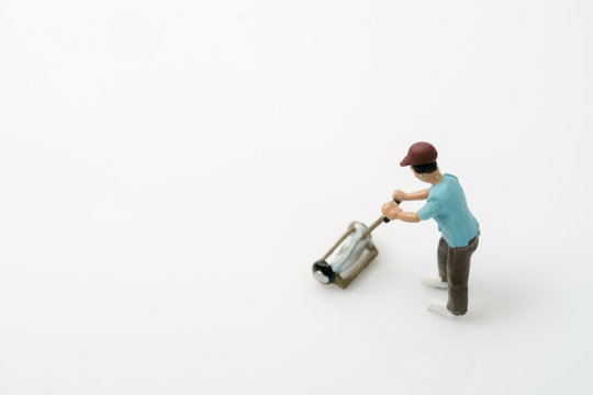 Toy people / View of miniature toy worker with lawn mower on white background.
